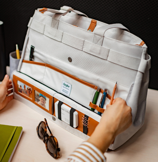 Gray organizer bag with compartments on a table, hands interacting with it.