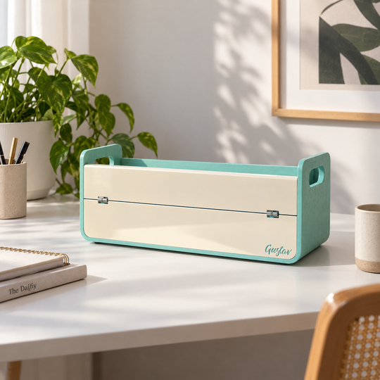 Gustag is a teal green and cream desk organizer box and alaptop stand, styled on a white desk in a bright, modern room with a plant and framed art in the background.